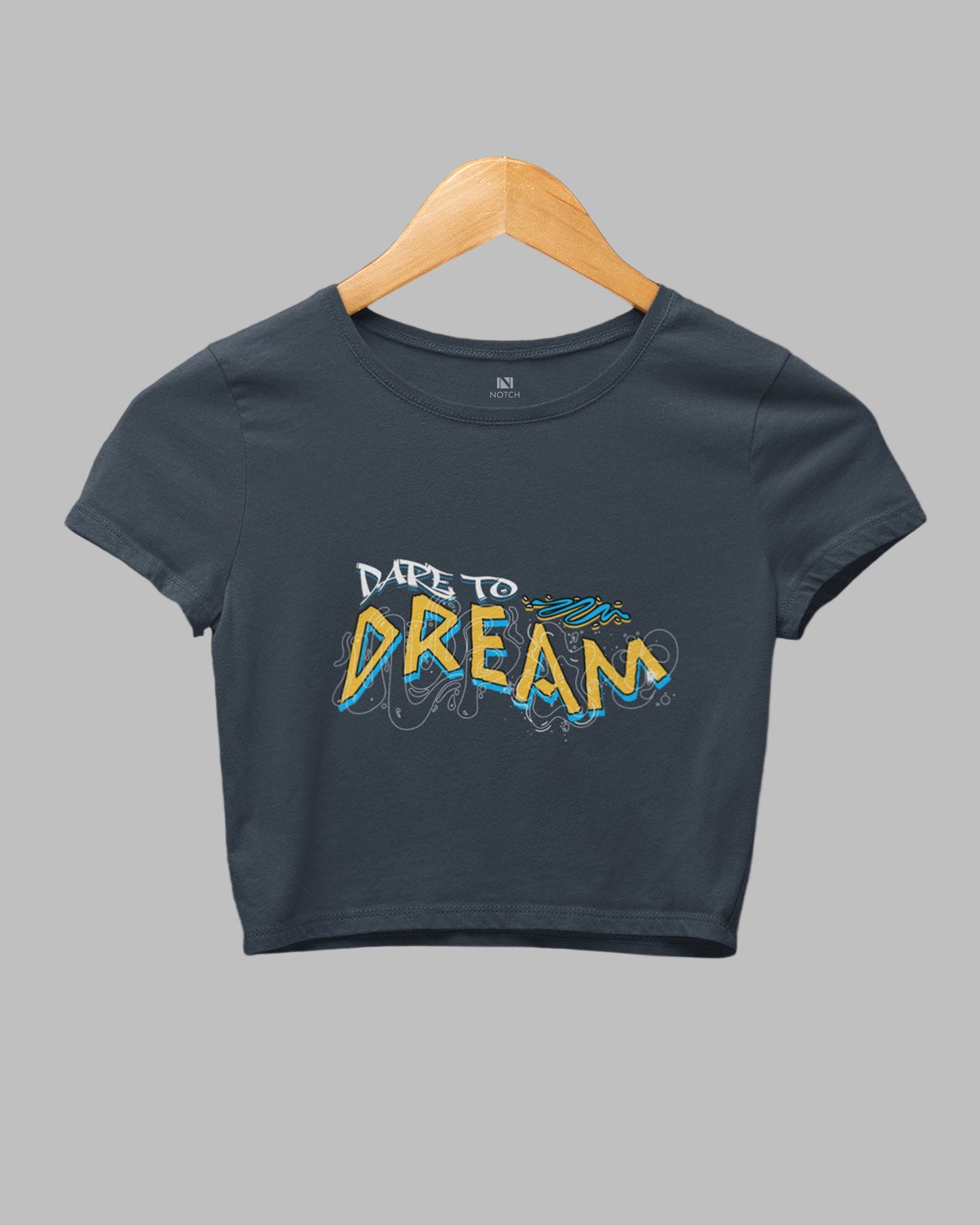 Navy blue t-shirt with 'Dare to Dream' text on a hanger against a dark background