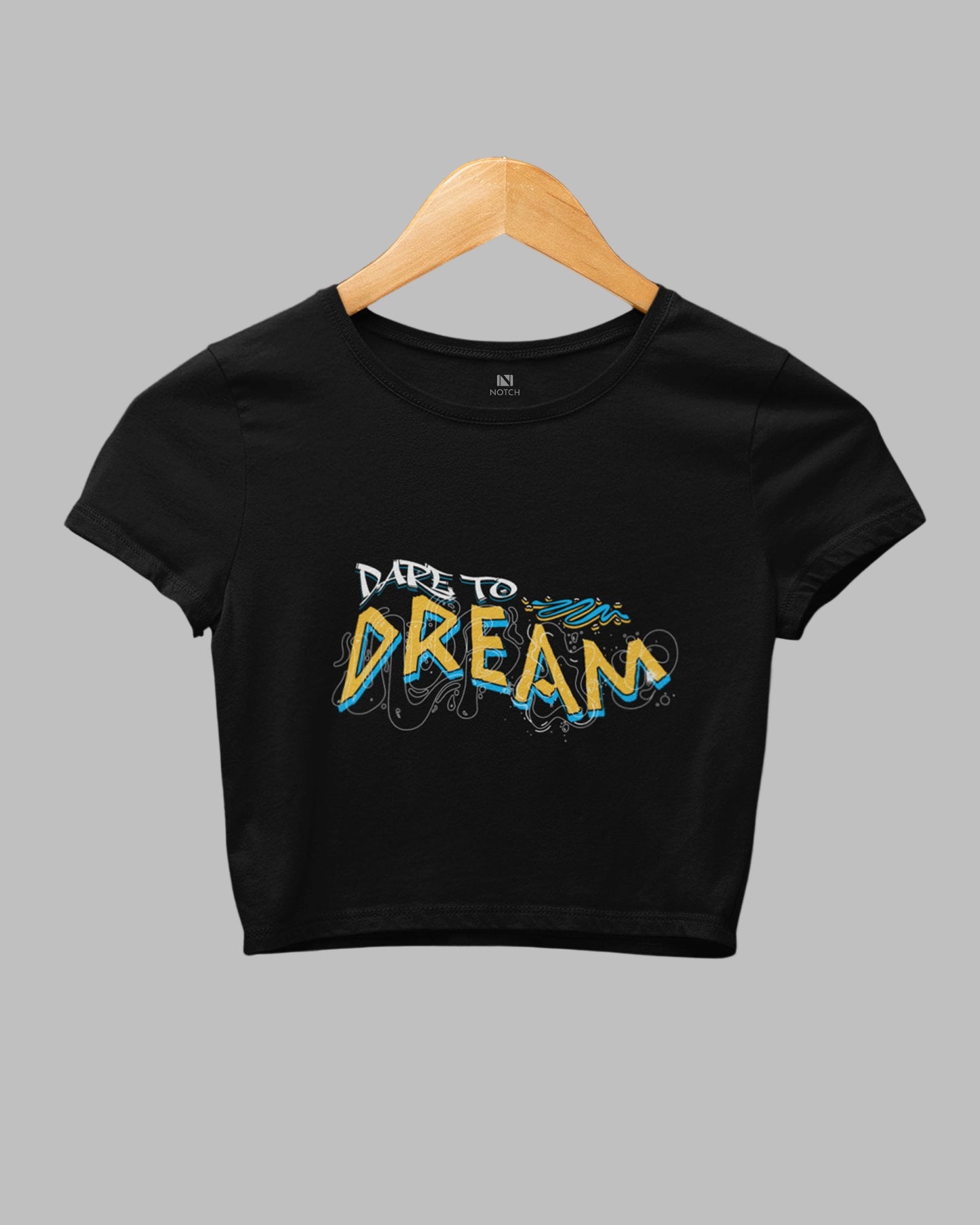 Black crop top with 'Dare to Dream' text on a hanger against a dark background