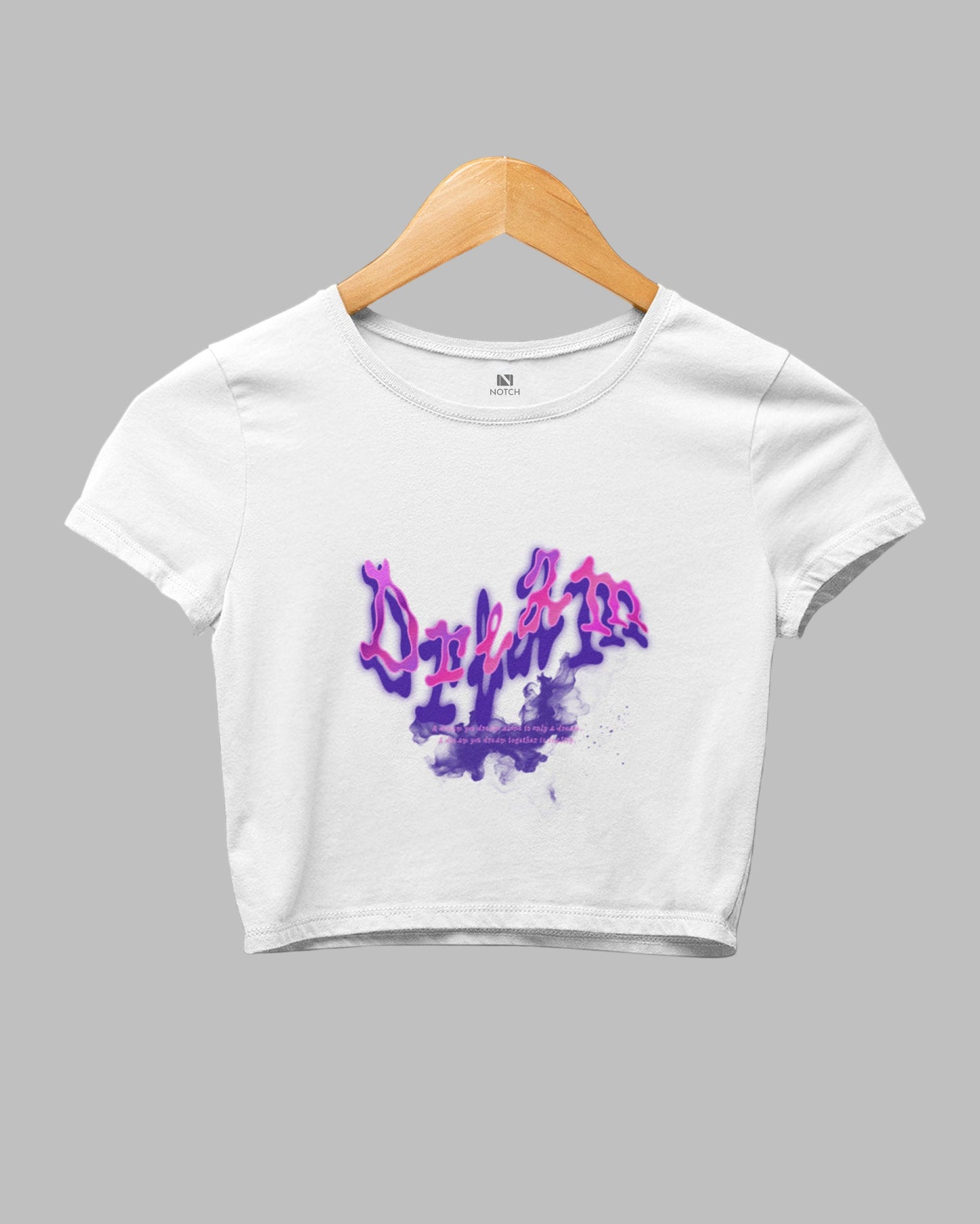 White crop top with colorful graphic on a hanger against a dark background