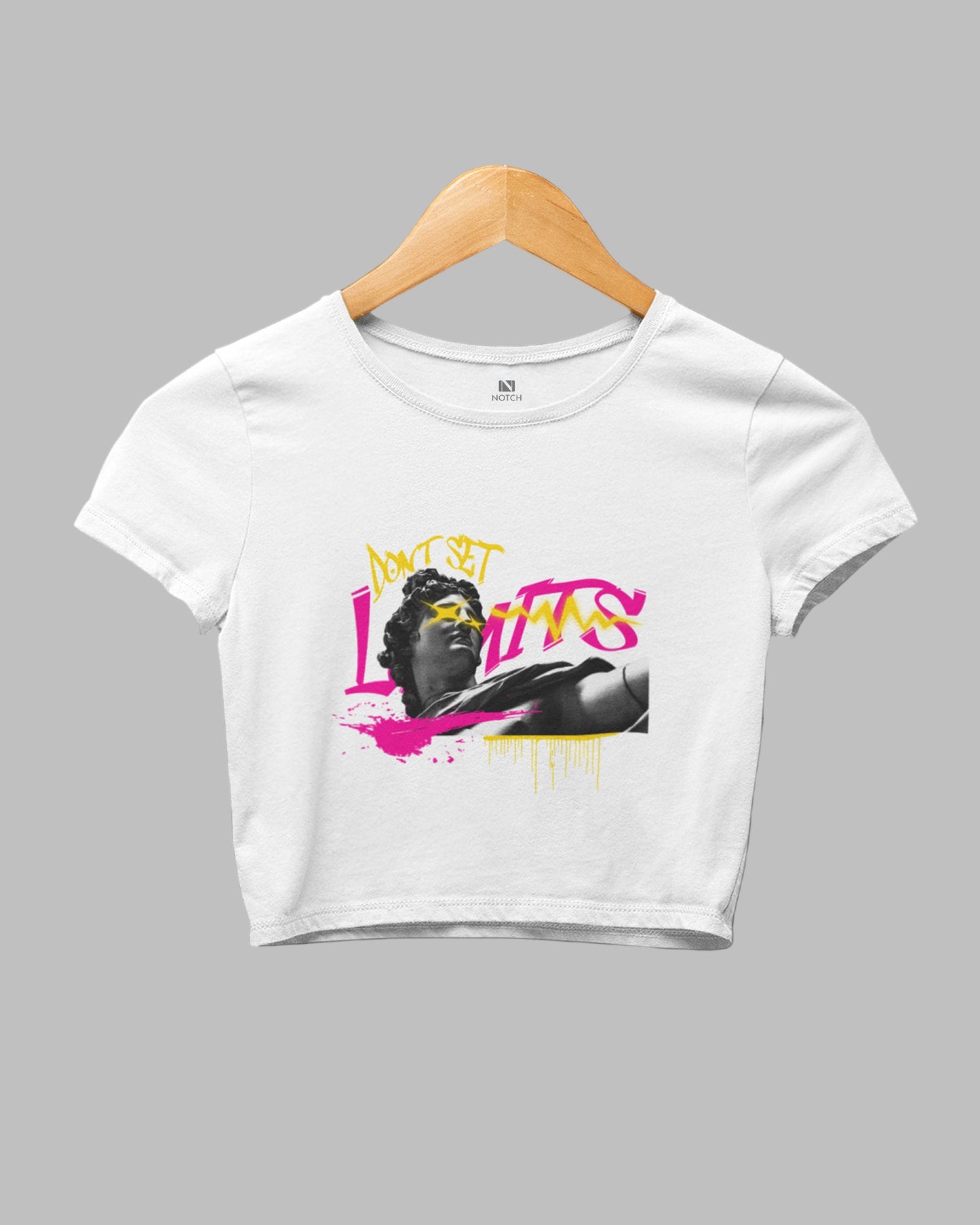 White crop top with graphic design on a hanger against a dark background