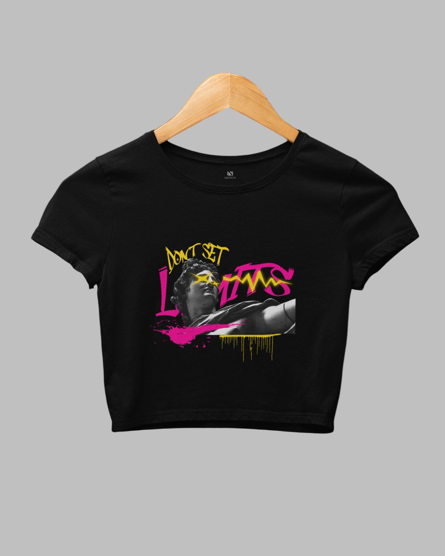 Black crop top with graphic design on a hanger against a dark background