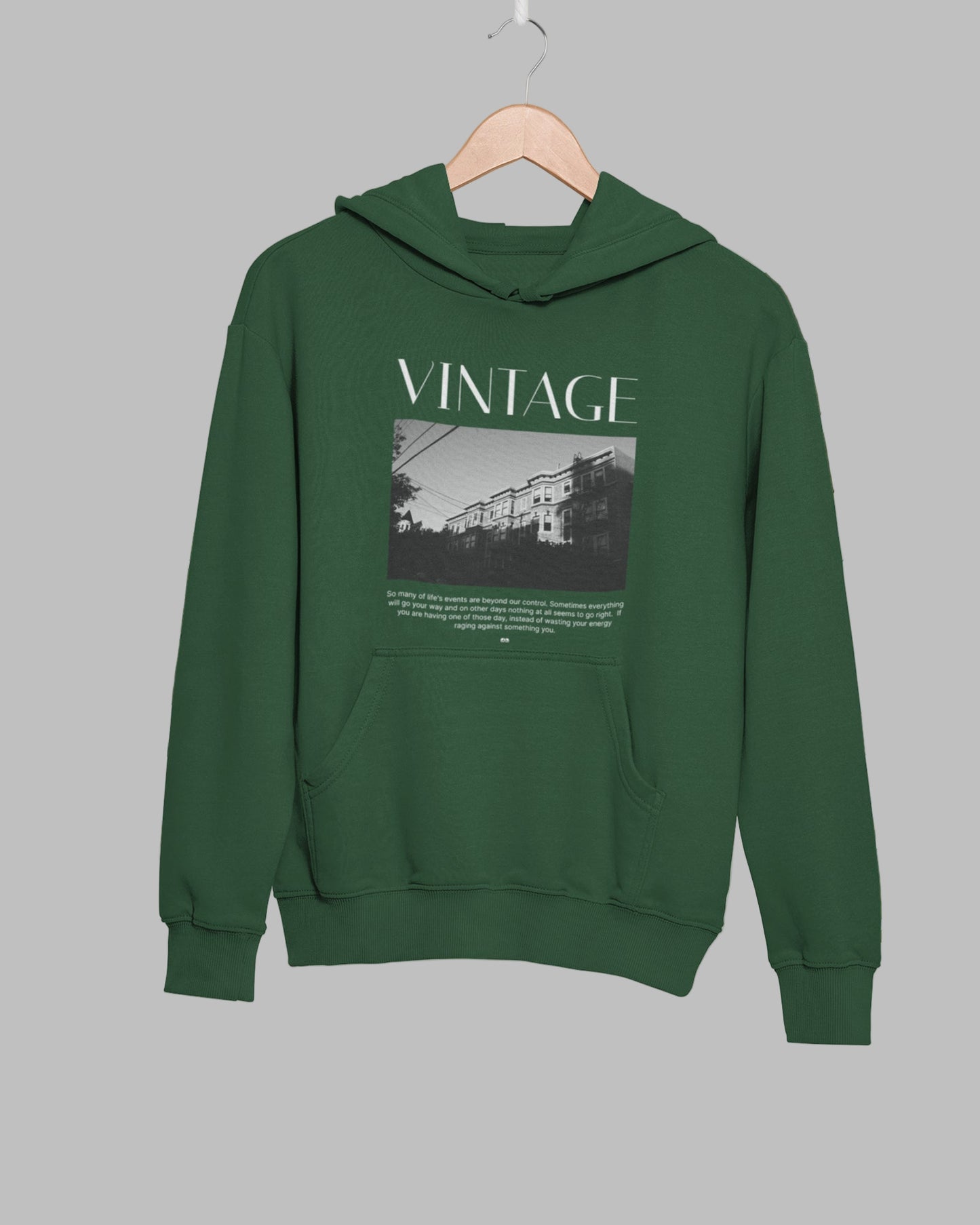 Green hoodie with 'VINTAGE' text and graphic on a hanger against a leafy background
