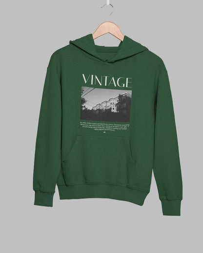 Green hoodie with 'VINTAGE' text and graphic on a hanger against a leafy background